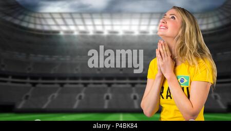 Fan de football brésilien en priant et en espérant en stade pour gagner Banque D'Images