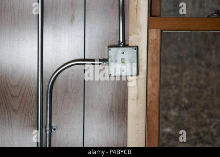 Old grunge metal monté en surface de l'interrupteur de l'électricité avec des tuyaux de conduite sur un mur lambrissé de bois Banque D'Images