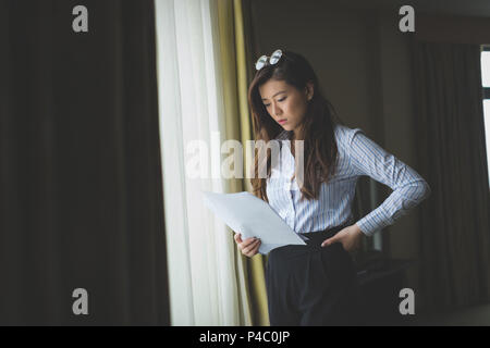 Businesswoman reading document fenêtre proche Banque D'Images