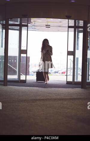 Businesswoman using mobile phone en arrivant dans l'hôtel Banque D'Images