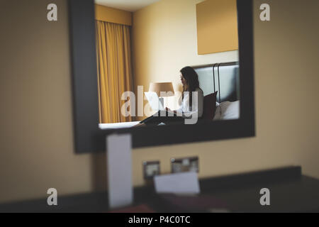 Businesswoman using laptop on bed Banque D'Images