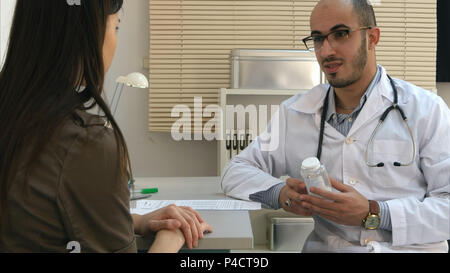 Homme médecin prescrivant comprimés au patient de sexe féminin et d'expliquer les effets secondaires Banque D'Images