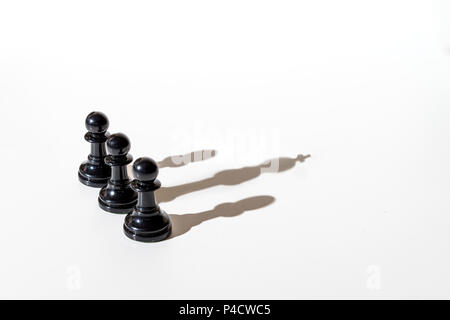 Trois pions d'échecs d'ombre, deux d'entre eux leur propre ombre et la troisième l'ombre du roi. La photographie conceptuelle qui peut illustrer concep Banque D'Images