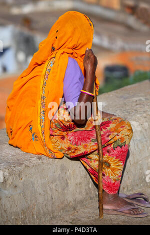 Femme en sari coloré assis sur un mur de pierre, Jaipur, Inde. Jaipur est la capitale et la plus grande ville de l'état indien du Rajasthan. Banque D'Images