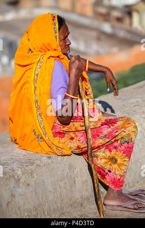 Femme en sari coloré assis sur un mur de pierre, Jaipur, Inde. Jaipur est la capitale et la plus grande ville de l'état indien du Rajasthan. Banque D'Images