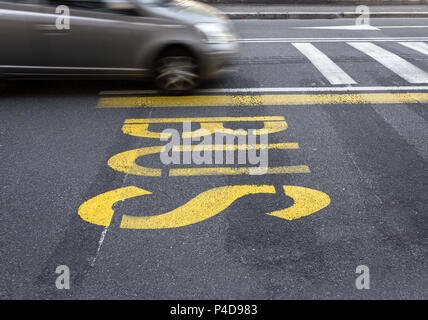 Bus jaune signe sur l'asphalte. Derrière, une voiture de flou artistique qui passe en vitesse. Banque D'Images