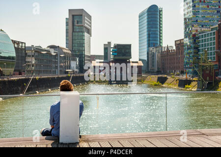 L'homme reposant sur une promenade dans le port de Düsseldorf Banque D'Images