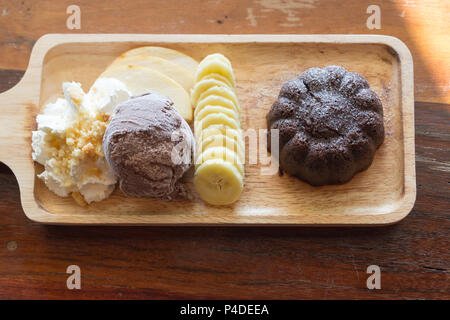 Jeu de gâteau au chocolat, avec la lave glace chocolat banane pomme fruit et crème fouettée sur table en bois dans le café, dessert de l'été. Banque D'Images
