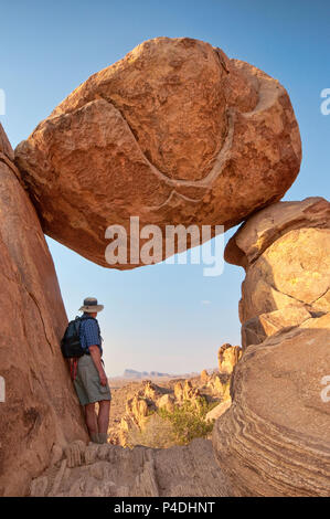 Randonneur à Balanced Rock, également connu sous le nom de The Window, à Grapevine Hills Trail, Chisos Mountains in Far distance, dans le parc national de Big Bend, Texas, États-Unis Banque D'Images