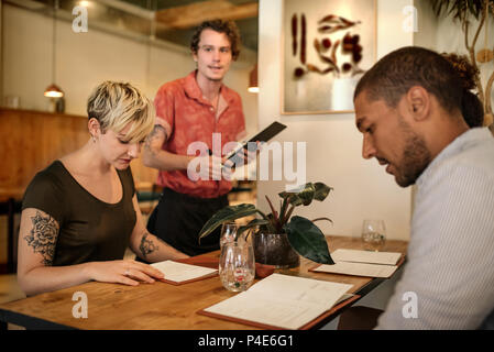 Groupe de jeunes amis de commander de la nourriture dans un restaurant. Banque D'Images