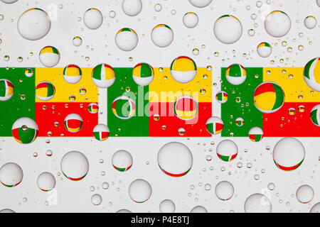 Drapeaux du Bénin derrière un verre recouvert de gouttes de pluie. Banque D'Images