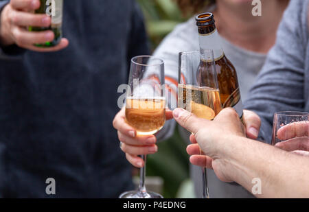 Friends toasting with drinks (lager et Xavier) à un rassemblement social extérieur Banque D'Images