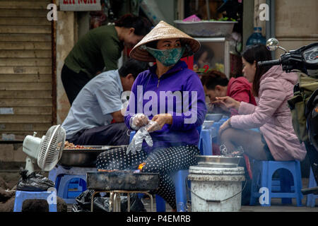 Hanoi, Vietnam - Mars 16, 2018 : l'alimentation de rue locaux vendeur préparer un barbecue dans la rue Banque D'Images