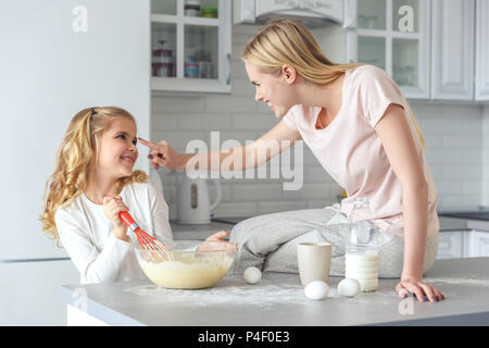 Jeune mère et fille jouer pendant la cuisson petit déjeuner ensemble Banque D'Images