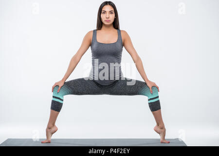 Enceinte asiatique woman practicing yoga in goddess pose, isolé sur gray Banque D'Images