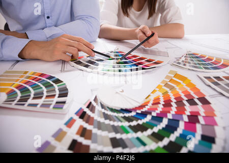 La main de l'architecte de deux choix de couleurs différentes nuances colorées Over Blueprint Banque D'Images