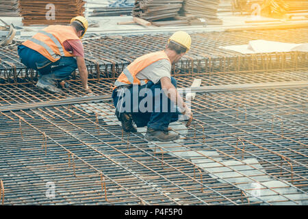 Les travailleurs de monteur travaillant sur des renforts en béton au chantier de construction. Monteurs de renfort. Vintage style. Banque D'Images