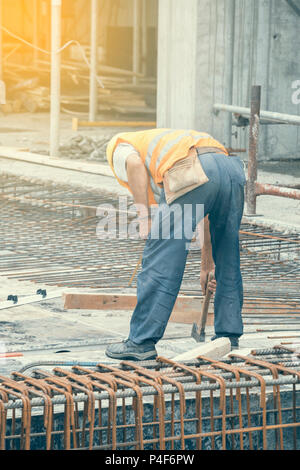 Monteur d'armature travaillant sur coffrage pour béton at construction site. Vintage style. Banque D'Images