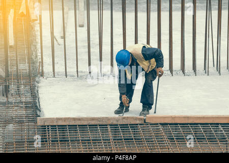 Travailleur avec crowbar dépose de coffrages en bois après le durcissement du béton. Déposer le moule en béton. Vintage style. Banque D'Images