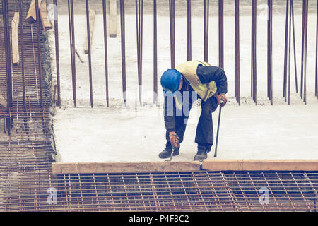 Travailleur avec crowbar dépose de coffrages en bois après le durcissement du béton. Déposer le moule en béton. Vintage style. Banque D'Images
