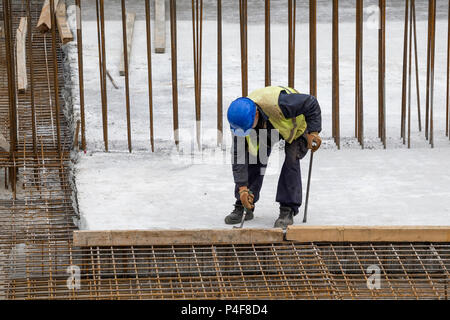 Travailleur avec crowbar dépose de coffrages en bois après le durcissement du béton. Déposer le moule en béton. Banque D'Images