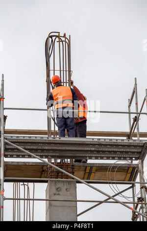 Les travailleurs sur la plate-forme d'échafaudage lié d'armature et de barres d'acier, pilier en béton en construction. Banque D'Images