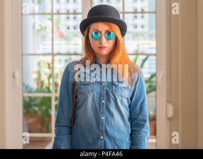 Rousse élégante femme portant chapeau melon et des lunettes sceptique et nerveux, fronçant bouleversé parce que de problème. Personne négative. Banque D'Images