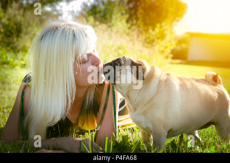 Woman kissing pug dog Banque D'Images