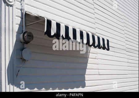 Auvent noir et blanc le long du côté du bâtiment, revêtement en bois peint en blanc. Banque D'Images