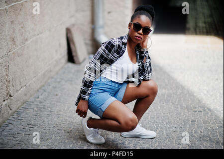 Le hip-hop african american girl sur des lunettes de soleil et des shorts jeans. Rue occasionnels fashion portrait de femme noire. Banque D'Images