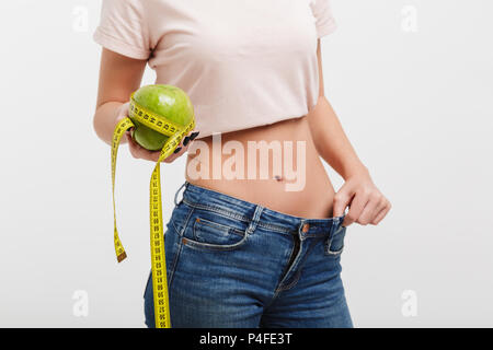 Cropped shot of woman holding apple attaché avec un ruban à mesurer isolated on white Banque D'Images