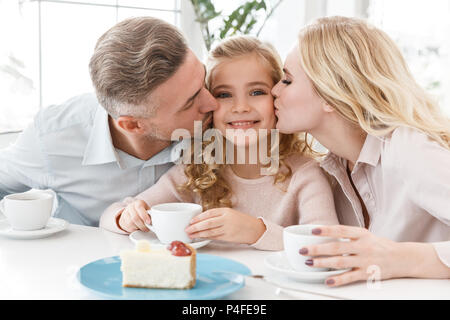 Les parents s'embrasser leur fille tout en passant du temps dans cafe Banque D'Images