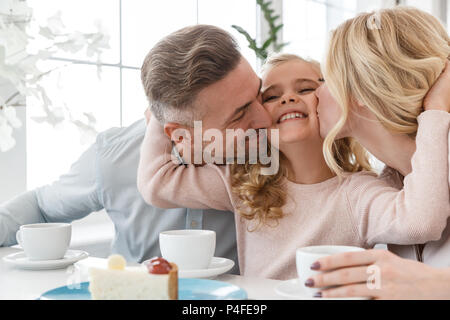 Embrassant leurs parens fille, alors passer du temps dans le café ensemble Banque D'Images