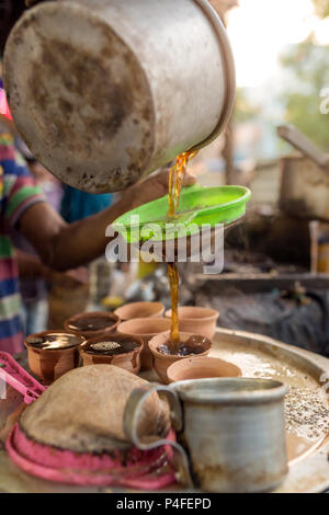 L'homme pour tasse de thé à l'Indienne ou chai pour les clients dans son magasin le long de la rue à Calcutta, Inde Banque D'Images