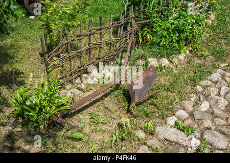 Old rusty metal charrue couché dans l'herbe près de la clôture Banque D'Images