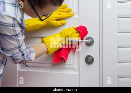 Service de nettoyage professionnel. Femme de ménage essuie le porte avec chiffon. Banque D'Images