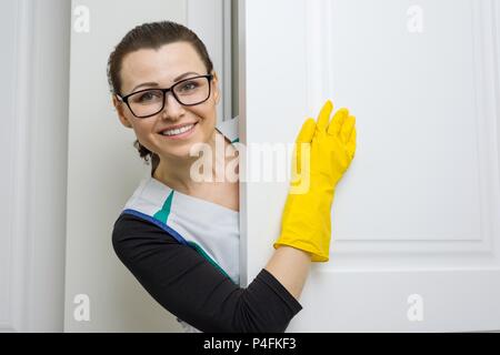 Service de nettoyage professionnel. Emploi femme gants en caoutchouc jaune en pointant avec un doigt vers la porte blanche est le lieu de l'espace de copie Banque D'Images