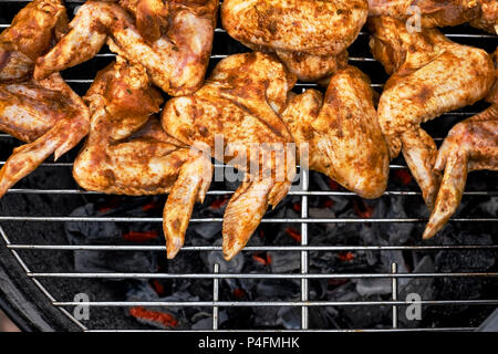 La cuisine épicée des ailes de poulet grillées sur un barbecue d'été avec des flammes chaudes Banque D'Images