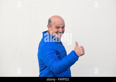Homme mature en veste bleue showing thumb up. L'émotion du visage positif Banque D'Images