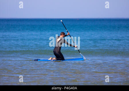 Un homme dans le paddle à la mer turquoise au cours de Whitsand Bay météo chaude et ensoleillée, Cornwall, UK Banque D'Images