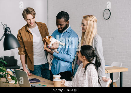 African American businessman holding Jack Russell Terrier et collègues souriant debout près de Banque D'Images