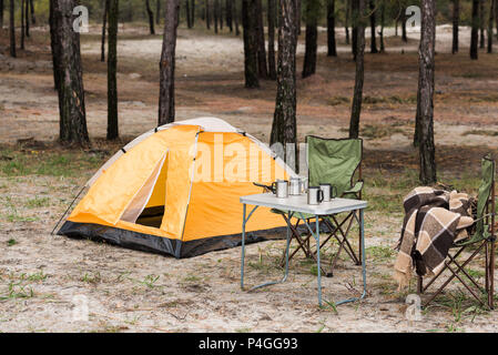 Tente de camping avec table et chaises debout dans forêt de pins Banque D'Images