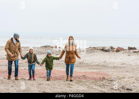 Beau jeune famille holding hands par mer sur jour d'automne Banque D'Images