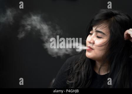 Une femme posent pour une photo alors que vaping lors d'une cigarette électronique juste à Jakarta, Indonésie. Banque D'Images