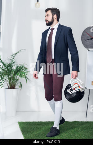 Jeune homme avec casque de rugby in office Banque D'Images