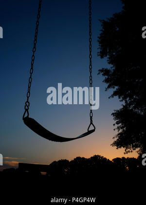 Silhouette d'un swing vide de l'aire de jeux en face de l'aube avant l'arrivée des enfants au Lac Benson Park à Garner Caroline du Nord. Banque D'Images