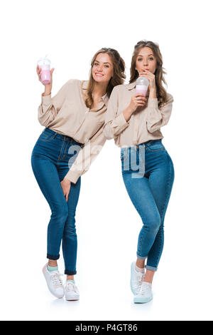 Smiling attractive young twins boire des milkshakes isolated on white Banque D'Images