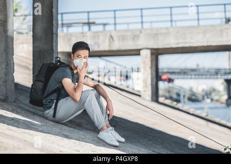 Masque de protection de l'adolescence dans asiatique assis sous le pont, la pollution de l'air concept Banque D'Images