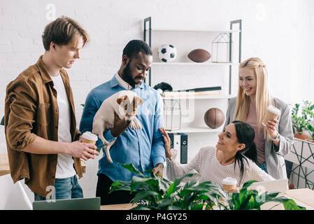 African American businessman holding Jack Russell Terrier et collègues souriant debout près de Banque D'Images