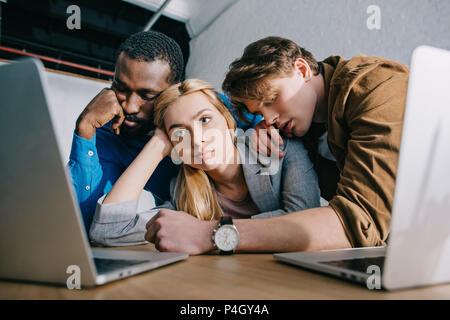 Two businesswomen avec deux collègues masculins à dormir sur les épaules sitting at table Banque D'Images